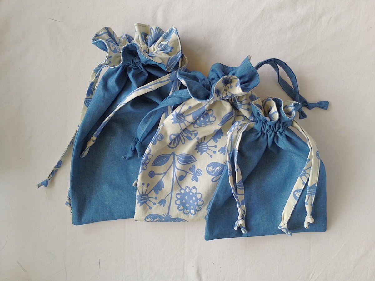 Three lined drawstring bags of various sizes made from blue and white floral patterned fabric.