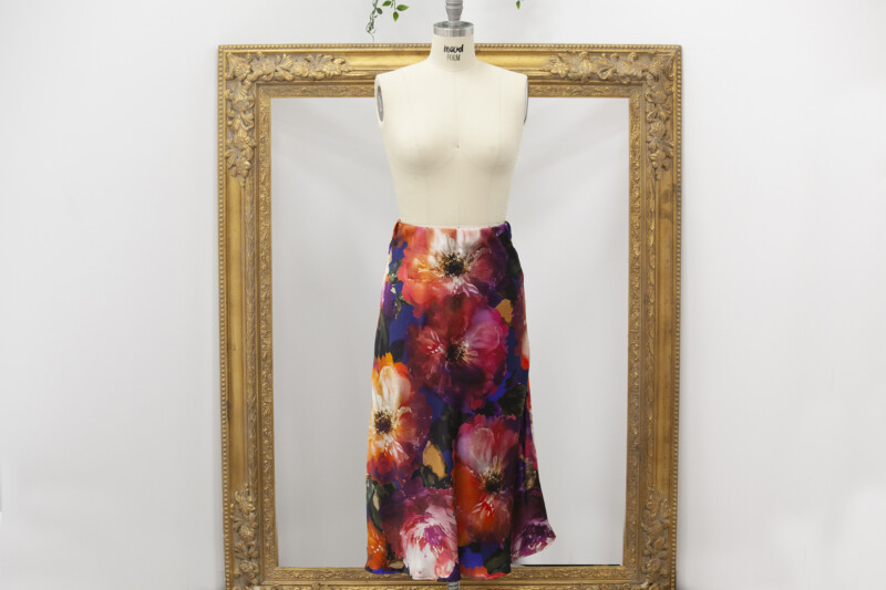 Floral bias cut midi skirt displayed on a dress form in front of an ornate gold frame.