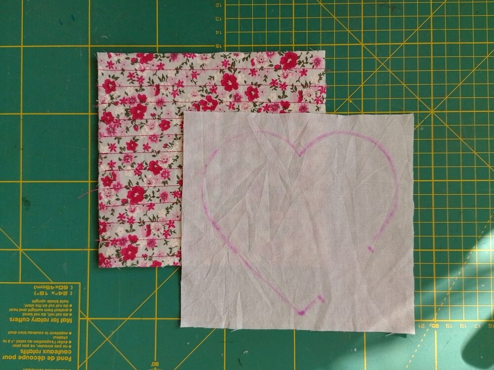 Two rectangular pieces of fabric. One is floral and the backing fabric is plain and has a heart shape traced on it.