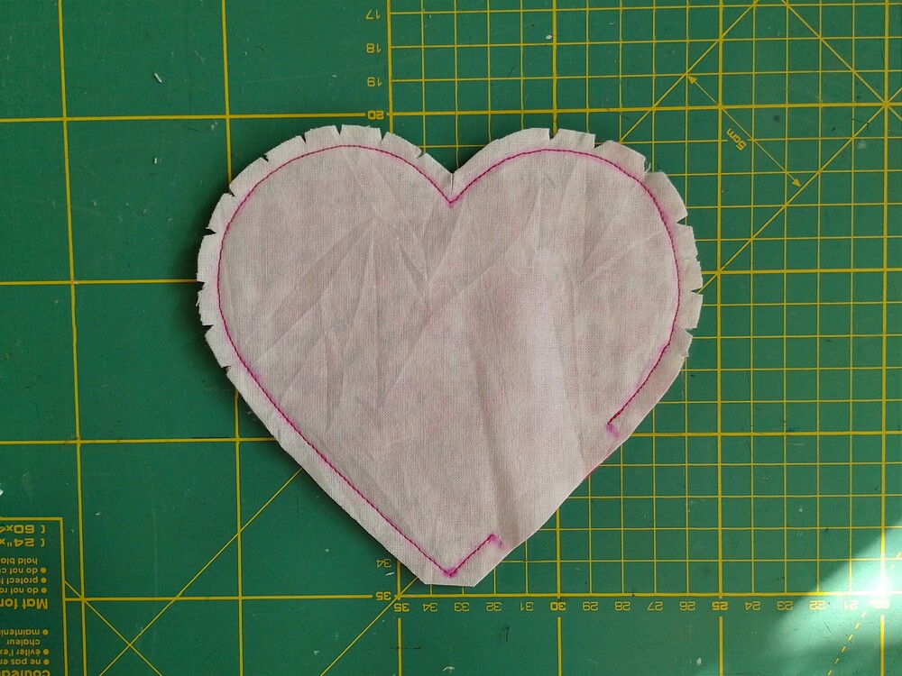 An inside-out heart shaped coaster with notches cut into the curves of the heart.