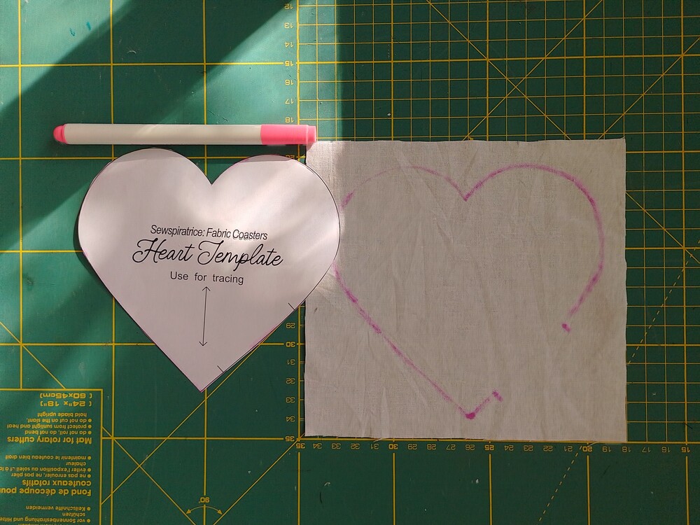 a heart shaped coaster template, pink erasable marker and white rectangle of fabric