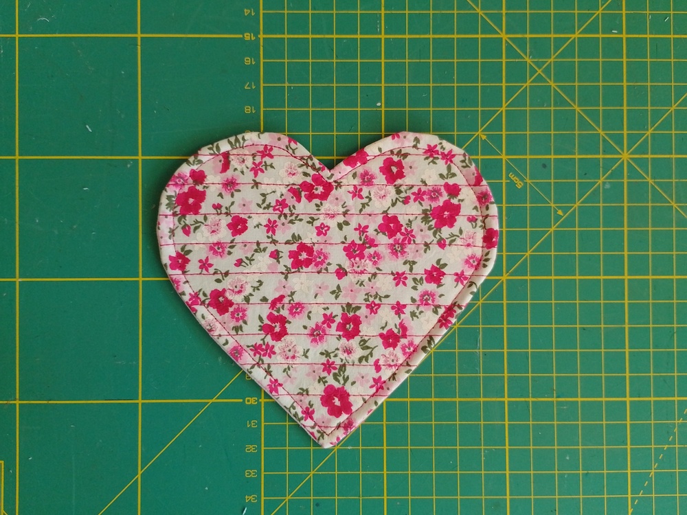 A heart shaped fabric coaster with top-stitch around the heart shape.