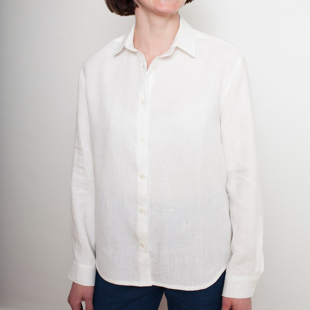 Person wearing a white linen button-up shirt with long sleeves and a classic collar.