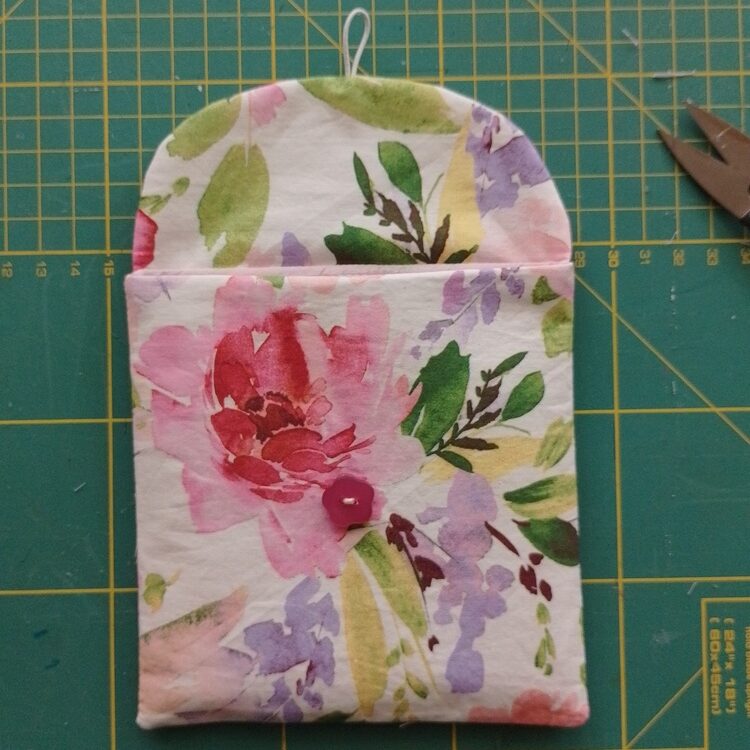 Sanitary pad pouch laid flat with the flap open and button visible on the front.