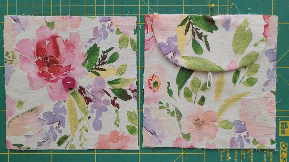 Two square fabric pieces, one with the flap attached at the top, and one with a button sewn in the center.
