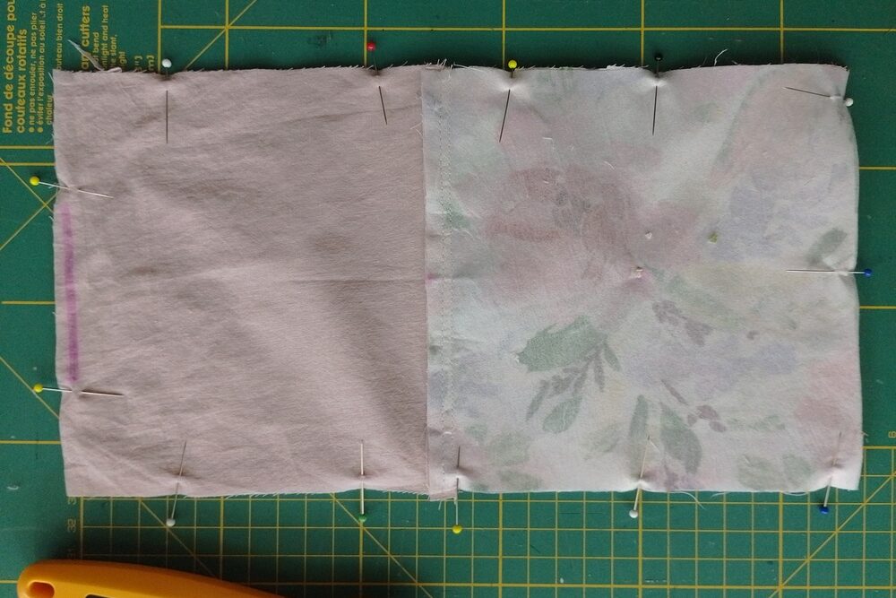 Pouch panels pinned right sides together, with pins around the edges and a gap on the lining side marked in a magenta.