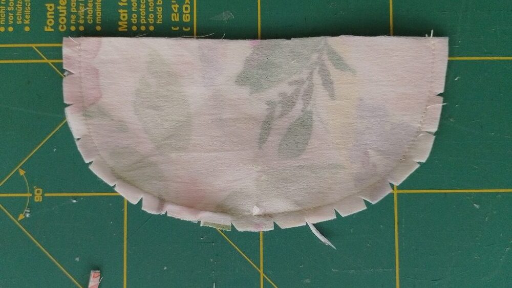 Flap piece with curved seam with notches cut into the seam allowance.