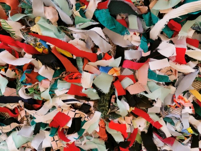 A close-up, overhead view of a large, messy pile of colourful fabric scraps.