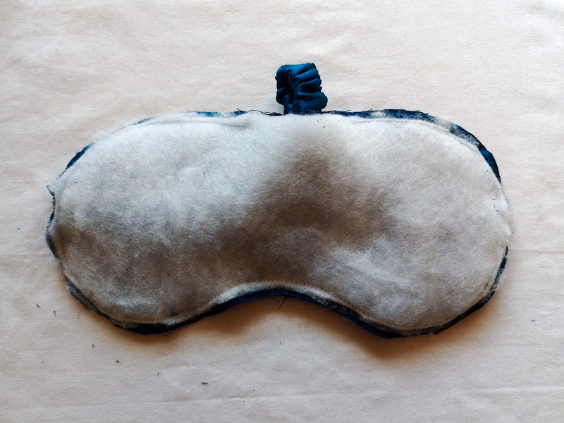 The inside of the eye mask, showing a layer of white batting trimmed to the shape of the mask, surrounded by a teal fabric seam allowance.