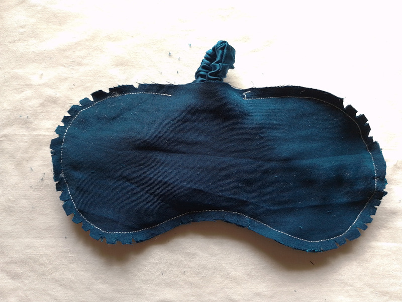 The teal eye mask with its outer seam allowance clipped into small notches all the way around the curved edges.