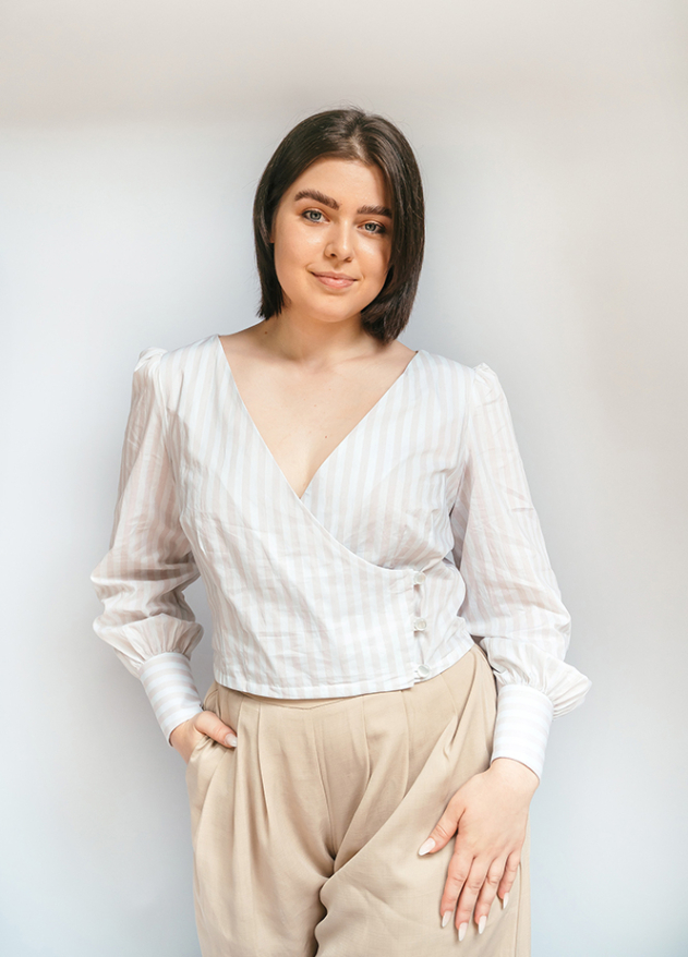 A woman models a light-colored striped wrap blouse with long cuffed sleeves.