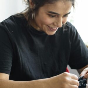 A smiling young woman works at a sewing machine.