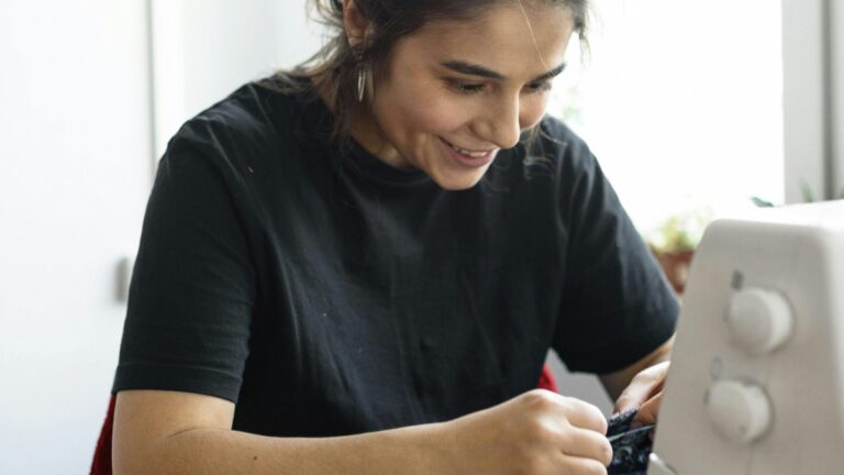 A smiling young woman works at a sewing machine.