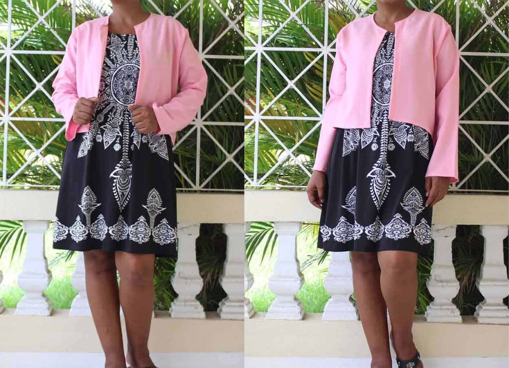 A woman wearing a short, open-front pink cardigan over a black and white patterned dress.