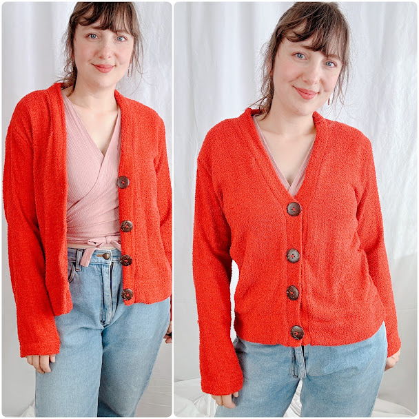 A woman wearing a bright orange, V-neck cardigan with large buttons, made from a textured bouclé fabric.