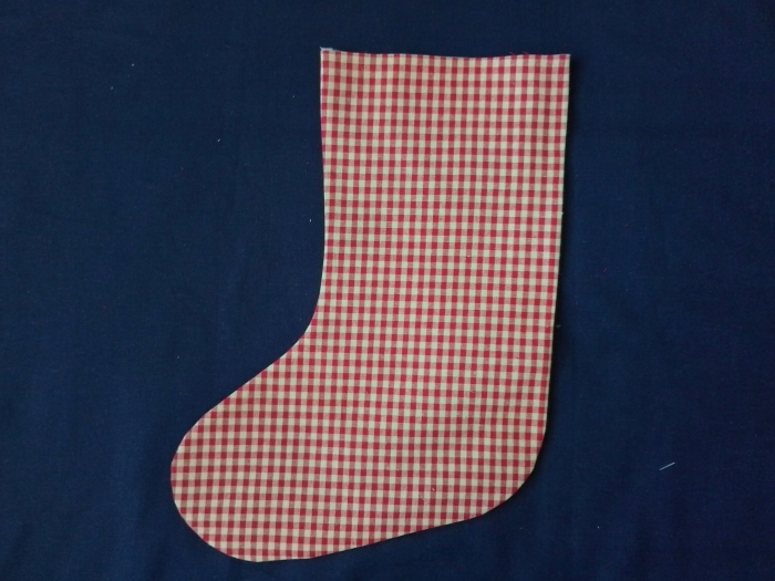 Christmas stocking made from red and white gingham fabric, turned right side out and pressed flat on a dark blue background.