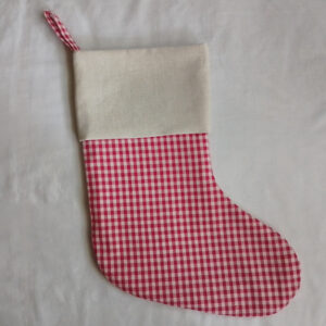 A finished Christmas stocking with a red and white gingham body and a solid off-white cuff, lying flat on a white background. A gingham hanging loop is visible at the top.