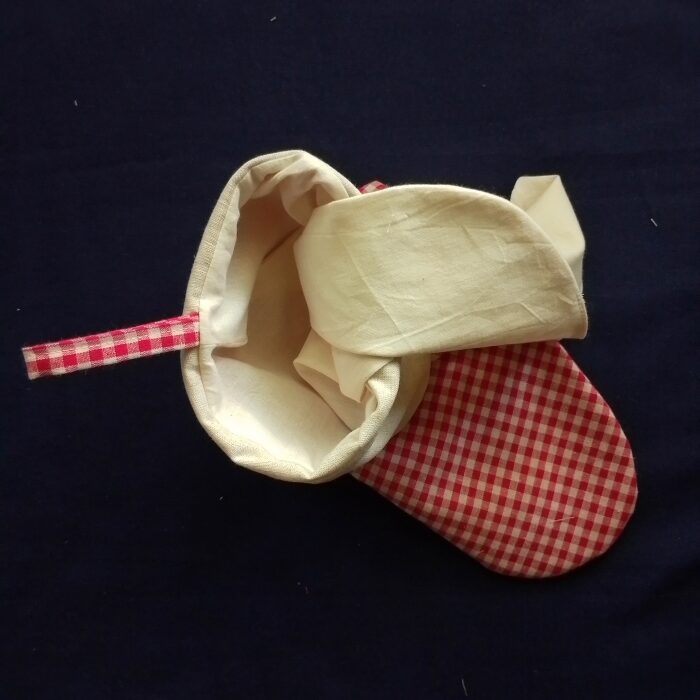 A top-down view showing an off-white stocking lining being tucked into the main red and white gingham stocking. The gingham hanging loop is visible on the left.