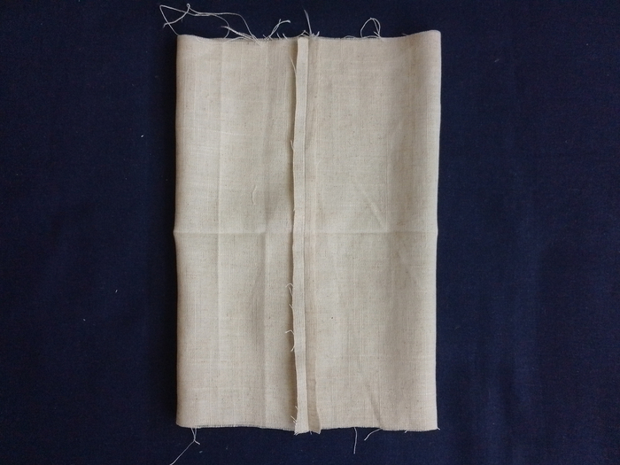 An open tube of off-white linen fabric with the side seam allowances pressed open flat.