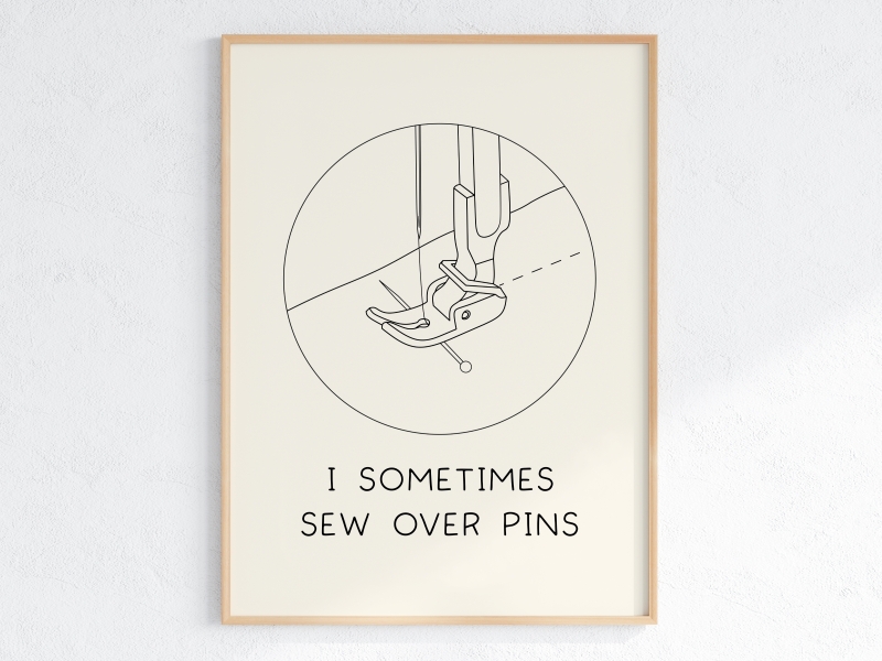 A framed line art print with an illustration of a sewing machine presser foot and the quote 'I sometimes sew over pins'