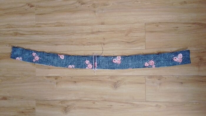 The inner and outer waistband pieces sewn together along the top curved edge, lying flat on the floor.