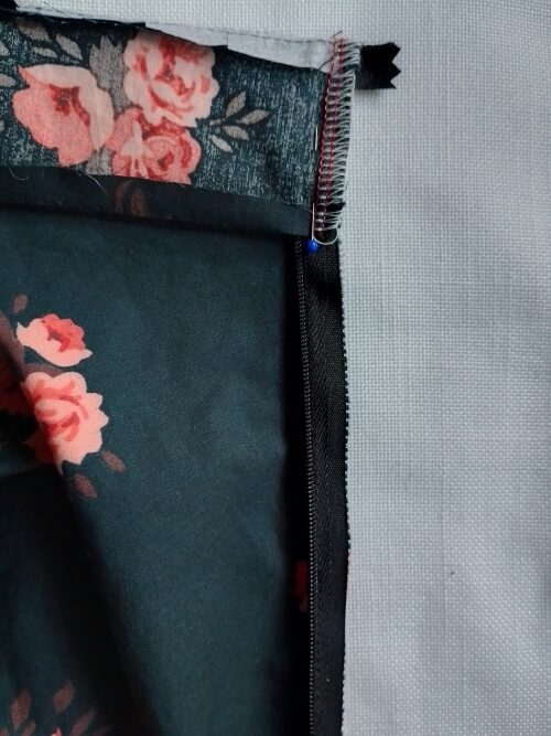 The outer waistband folded down over the zipper tape, right sides together, and pinned in place.