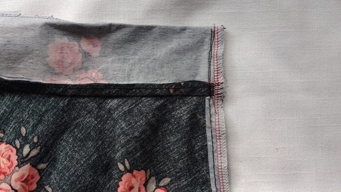 he waistband corner sewn wrong-side-out, showing the vertical stitching line that encloses the end of the zipper tape.
