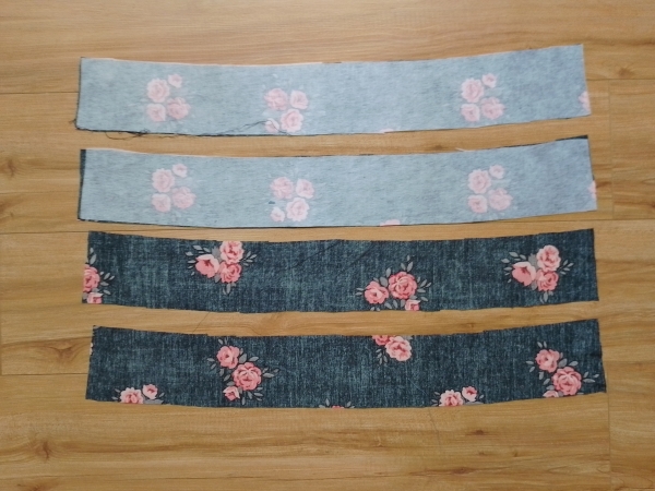 The four curved waistband pieces. Two of the pieces have white fusible interfacing applied to their wrong side.