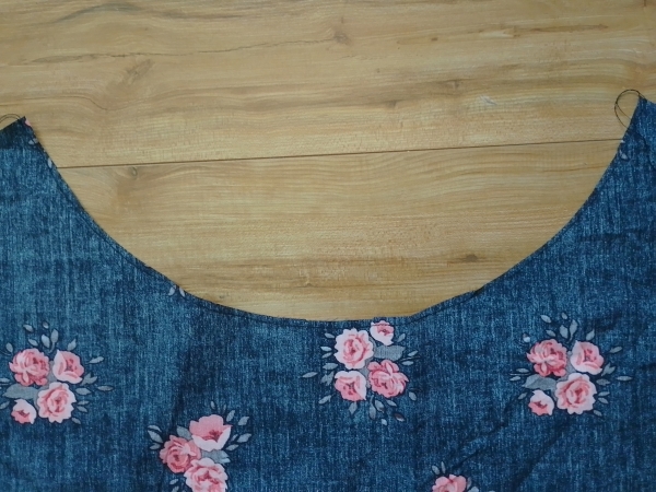A close-up of the curved waistline of the floral skirt piece, showing a line of staystitching sewn near the raw edge.
