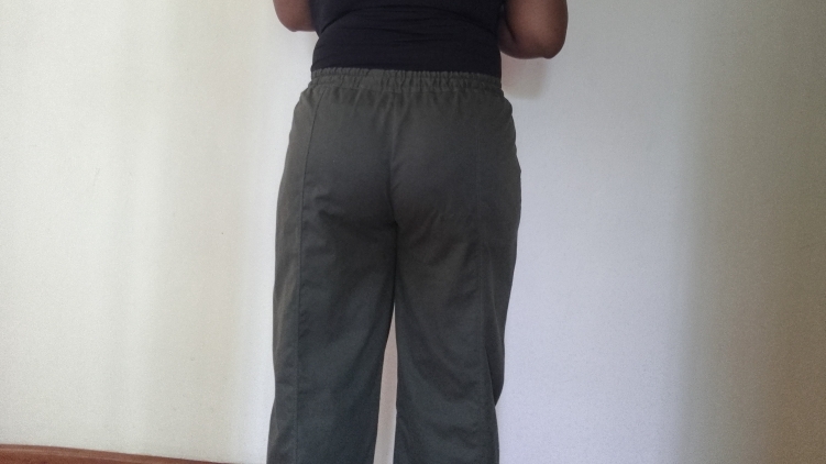 Back view of dark green elasticated wide-legged pants worn by a person, showing a fit issue where the back rise appears low.