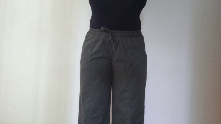 Front view of dark green elasticated wide-legged pants with a drawstring worn by a person.