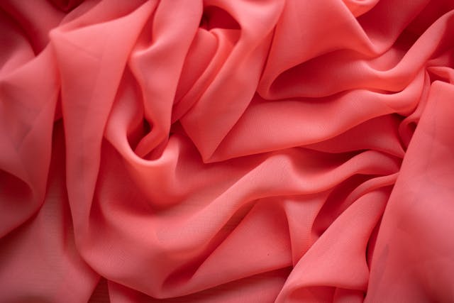 Close-up shot of lightweight, draped, coral coloured chiffon.