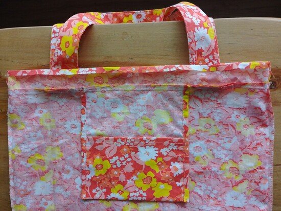 The inside of a tote bag with a pocket attached and the casing flipped upwards with the upper edge folded