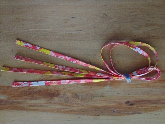Several finished floral fabric drawstrings clipped together on a wooden surface