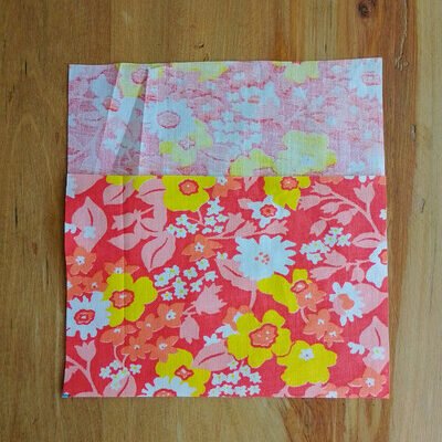 A rectanglee of floral fabric laid flat on a wooden table.