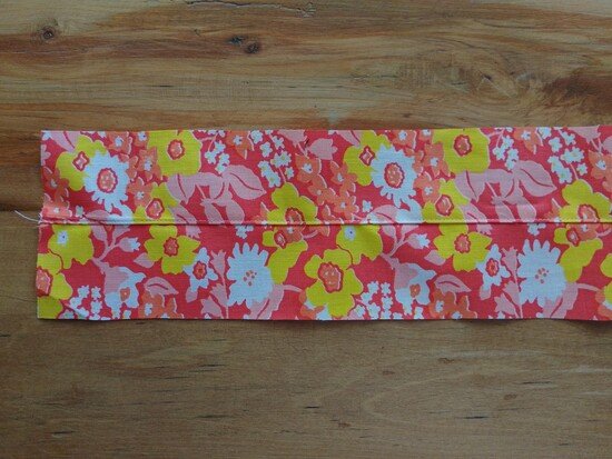 A floral fabric strap with the center seam pressed open on a wooden surface.