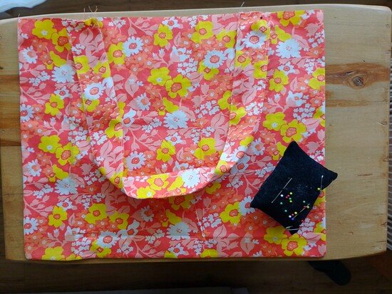 The straps of a tote bag pinned to the upper edge of the bag