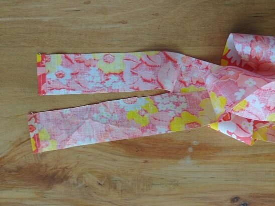 Two short floral fabric strap ends with stitched edges.