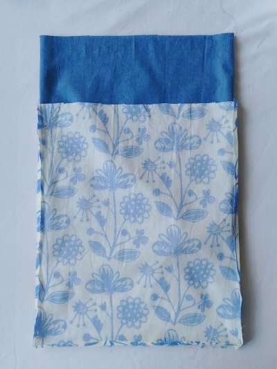 A blue chambray fabric pouch partially inserted in a printed blue and off-white floral fabric pouch.