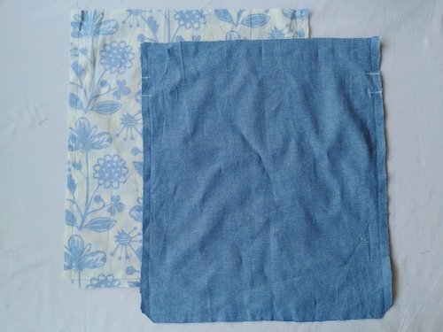 Two fabric pouches, one floral and one blue chambray, sewn and turned wrong side out with the bottom corners clipped.
