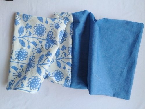 The floral main fabric and blue chambray lining pouches laid out end-to-end after being sewn together at the top edge.