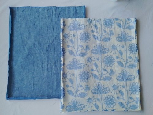 Two rectangular fabric pieces, one floral and one blue chambray, laid side-by-side with the seams pressed open