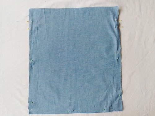 Two blue chambray fabric pieces turned wrong side out and pinned together