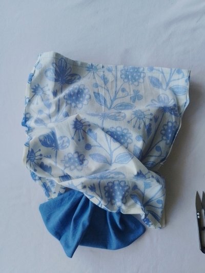 A floral fabric pouch being pulled out of a solid blue fabric lining.