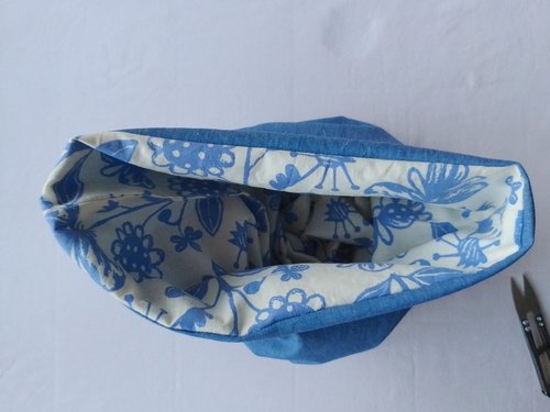 The top view of a pouch with the lining made of an off white and blue printed fabric and the outside, a blue chambray fabric.