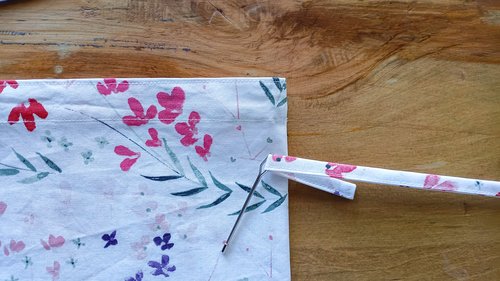 A bodin attached to a fabric drawstring, near a fabric bag.