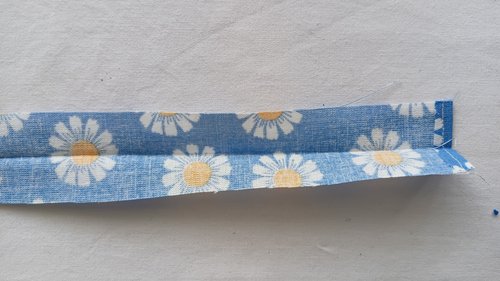 A long strip of blue floral fabric folded and creased down the middle.