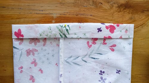 A sewn floral fabric bag turned inside out, showing the folded top edge and the side seam.