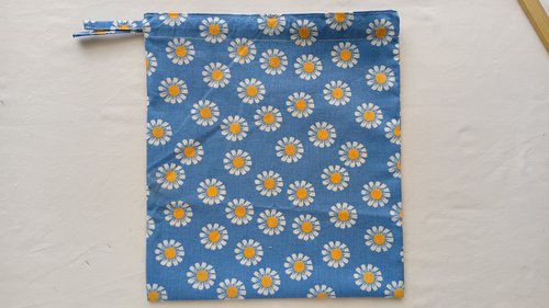 A blue floral drawstring bag with two fabric ties pulling out only from the left side.