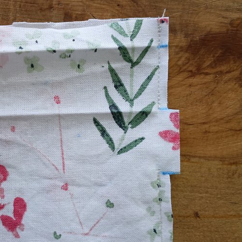 A close-up of the fabric edge showing a sewn line of stitches and a small rectangular notch cut out of the side.